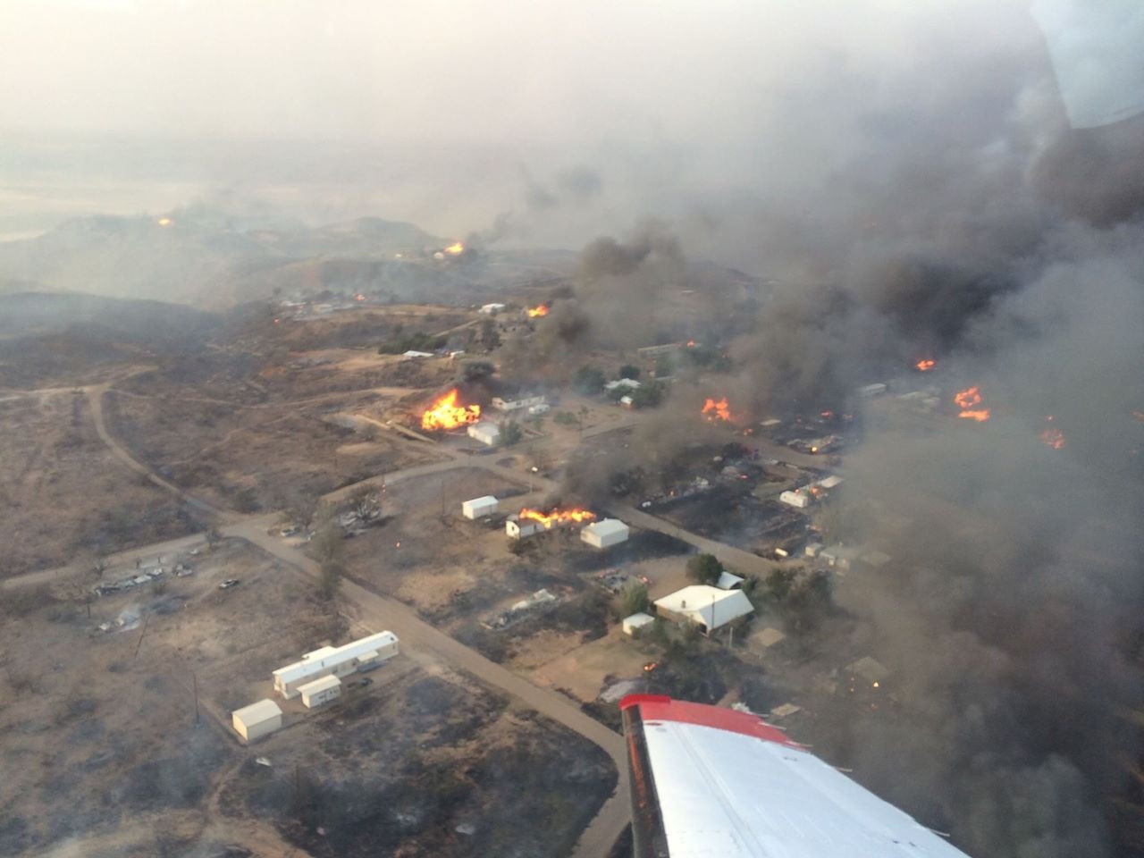 Aerial view of a wildfire in a community with smoke throughout the sky